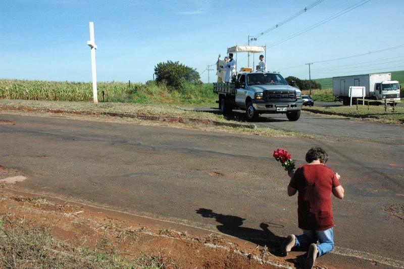 Mulher se ajoelha para a passagem do Santíssimo Sacramento 